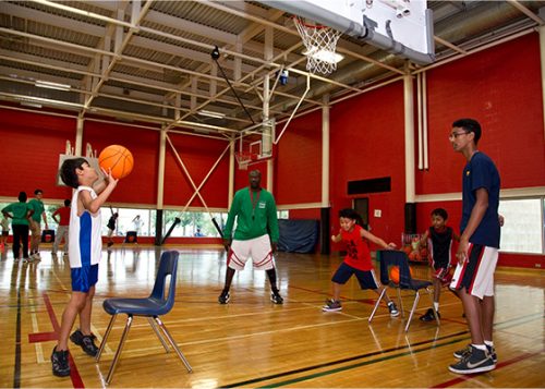 City staff members are coaching children in basketball inside the recreation center.