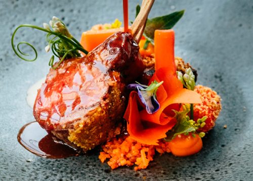 A lamb dinner plated artfully with colourful garnishes.