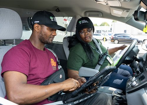 Two people sitting in a vehicle looking at tablet.