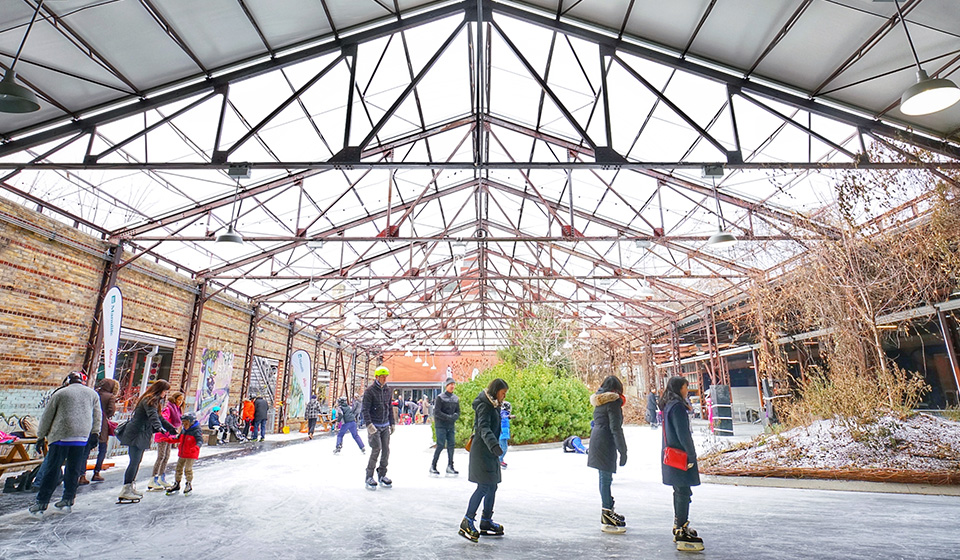 People skating around a Evergreen Brickworks with an open air barn like roof overhead.