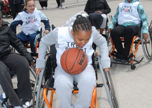 During wheelchair basketball play, a girl in a wheelchair holds the ball.