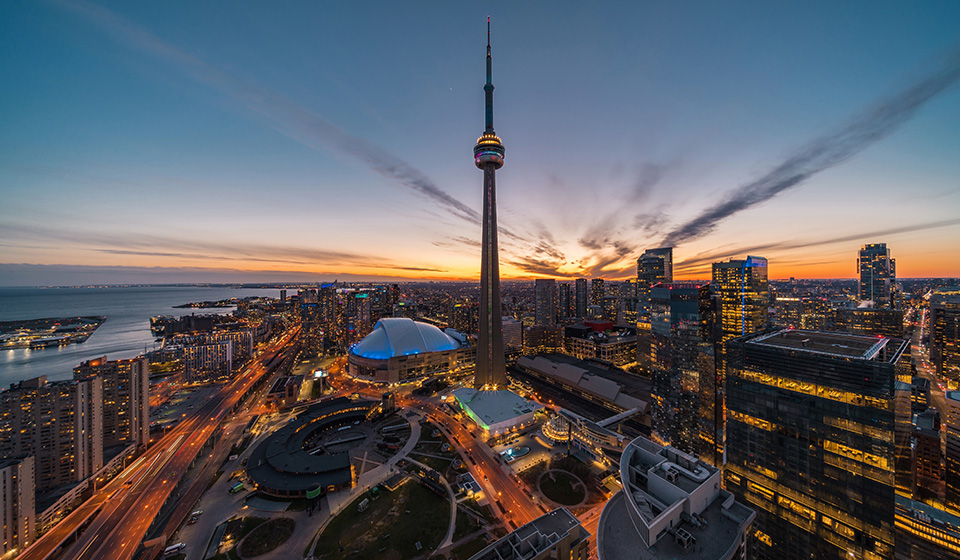 An aerial view of downtown Toronto at Sunset facing the CN Tower with the Lake Ontario in the background.