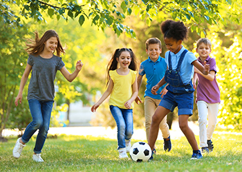 Children playing soccer in a green space.