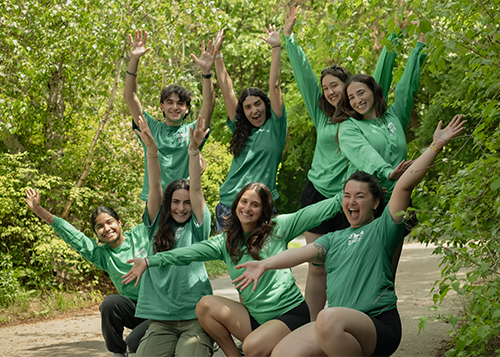 A group of people in green City of Toronto staff shirts standing in a tree lined path.