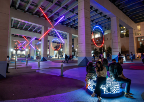 Large neon Xs and Os lit up in the night under an expressway