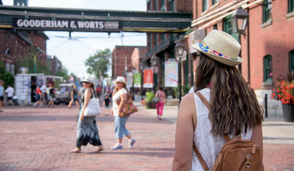 Woman wearing backpack stands on cobblestone street with historic buildings