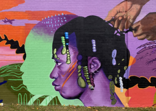 Vibrantly painted mural with a figure with purple skin having their hair done on the far right.